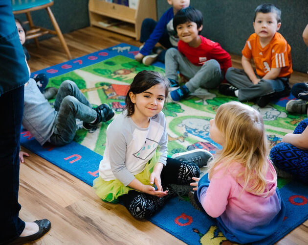Kids sitting on a carpet.