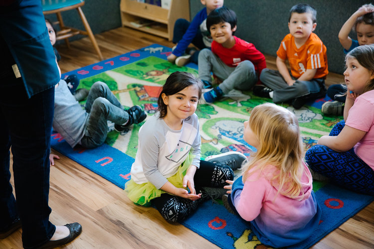 Kids sitting on a carpet.